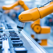 Robotic arm performing assembly on a production line in a modern manufacturing facility Robotic arm performing assembly on a production line in a modern manufacturing facility