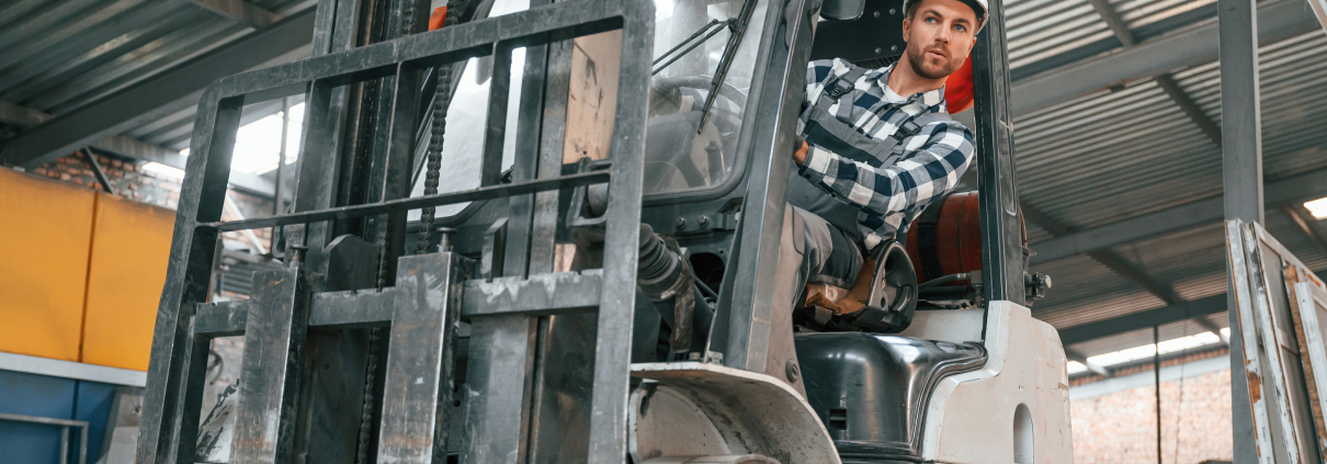 Inside of the forklift. Factory male worker indoors Inside of the forklift. Factory male worker indoors